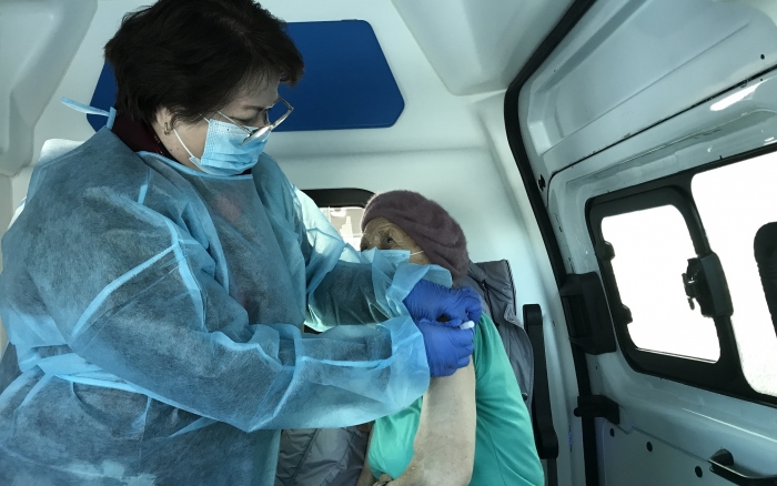 wnętrze ambulansu, w nim 2 osoby w trakcie wykonywania szczepienia