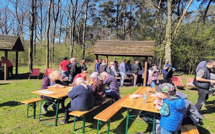 uczestnicy wydarzenia przy stołach na leśnej polanie