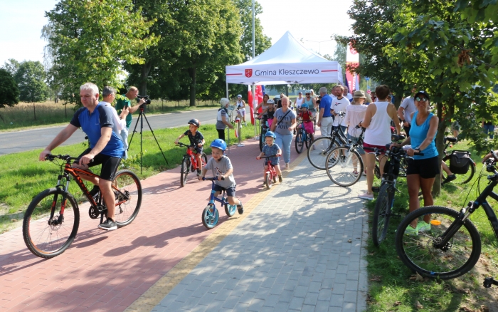 rowerzyści na starcie ścieżki rowerowej, wśród nich dzieci na rowerkach biegowych