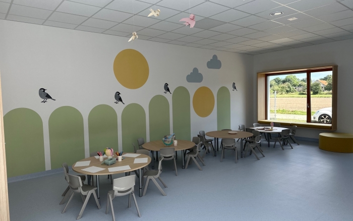 sala przedszkolna,  jasne ściany z kolorowymi akcentami, okrągłe stoliki z krzesłami dla dzieci, 