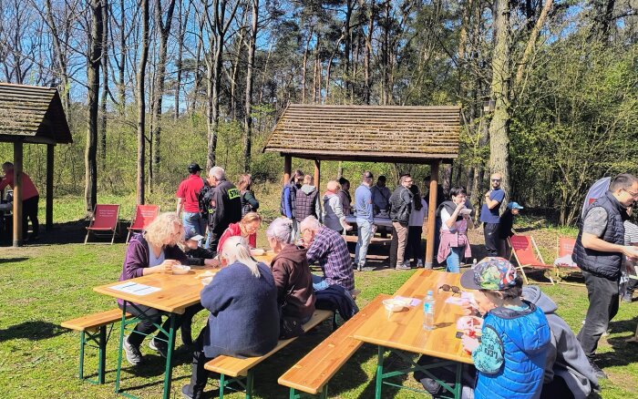 uczestnicy wydarzenia przy stołach na leśnej polanie